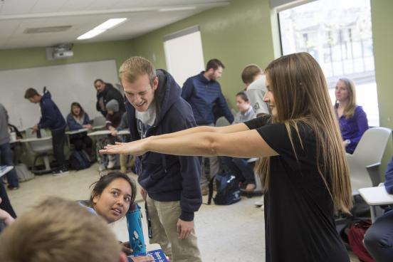 Two students examine another student's outstretched arms