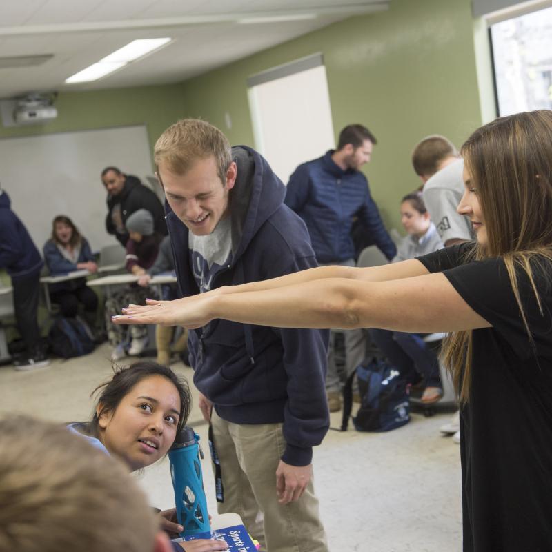 Two students examine another student's outstretched arms